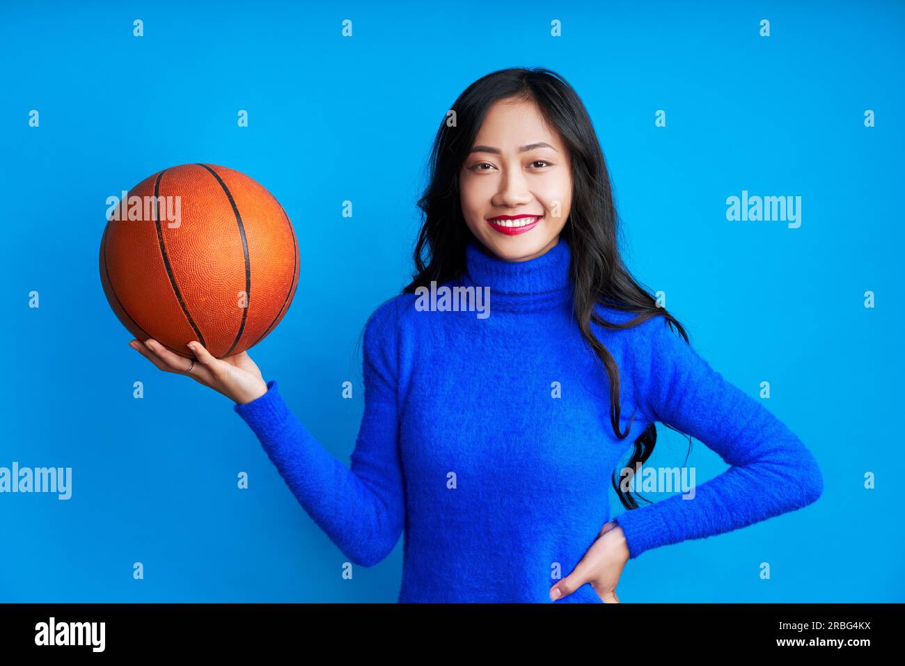 Junge hübsche Frau mit Basketball in der Hand isoliert auf blauem Hintergrund, Sport, Freizeitkonzept Stockfoto