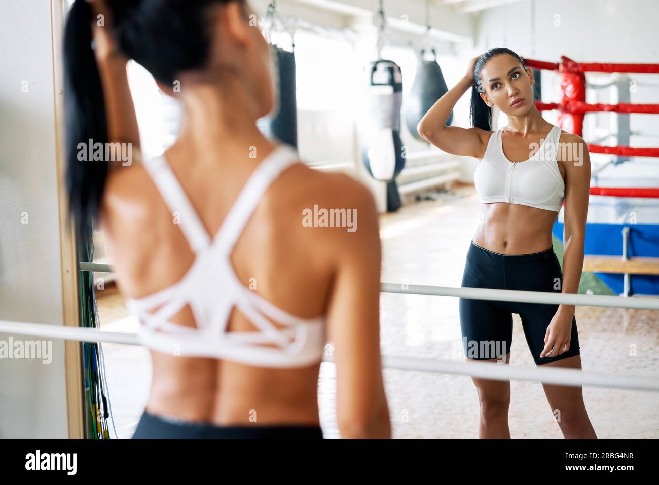 Rückansicht der fit-Frau, die sich im Spiegel im Fitnessstudio ansieht. Sportkonzept Stockfoto