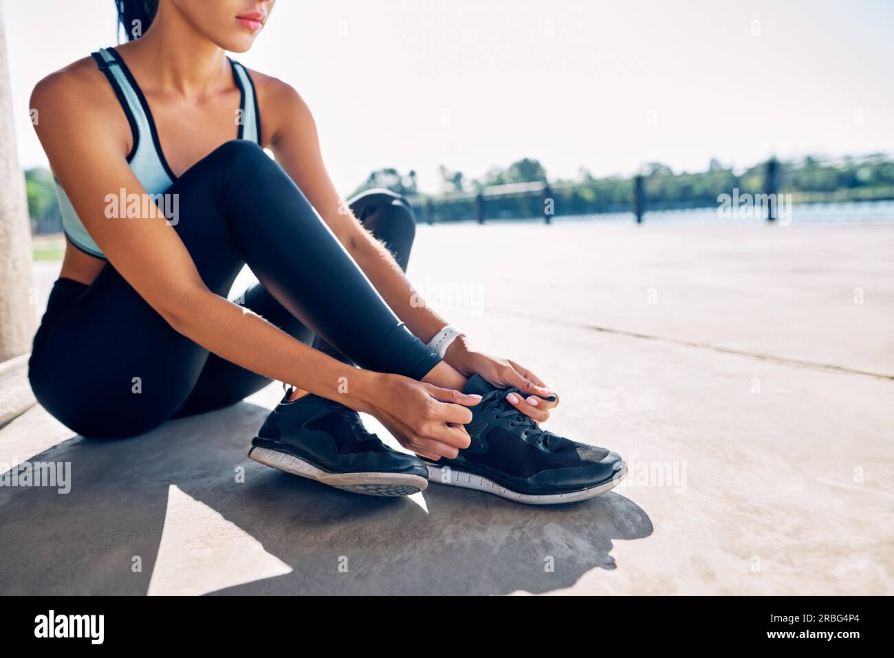 Junge Fitness-Frau Läuferin, die im Freien Schuhschnürsenkel bindet und sich zum Joggen bereit gemacht hat Stockfoto