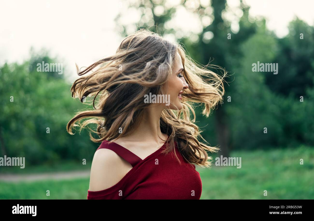 Junge glückliche Frau mit flatternden Haaren Spaß im Freien auf grünen Sommer Natur Hintergrund. Weibliches Schönheitskonzept Stockfoto