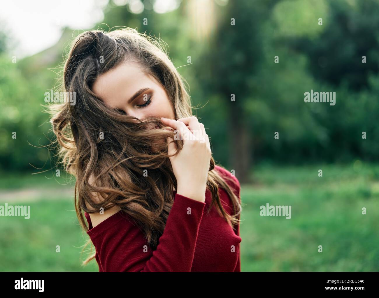 Junge glückliche Frau mit flatternden Haaren Spaß im Freien auf grünen Sommer Natur Hintergrund. Weibliches Schönheitskonzept Stockfoto