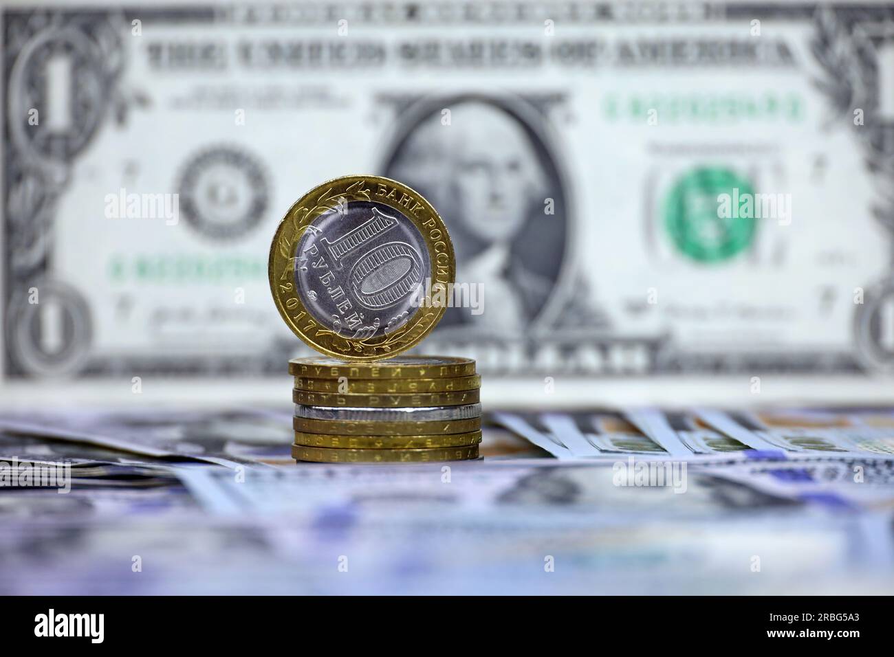 Russische Rubel-Münzen auf dem Hintergrund von US-Dollar. Konzept des Wechselkurses, amerikanische Sanktionen gegen die Wirtschaft Russlands, fallender Rubel Stockfoto