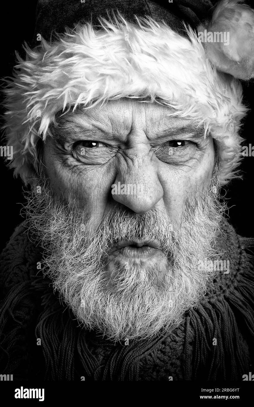 Schwarz-Weiß-Porträt eines erwachsenen Mannes mit weißem Bart verkleidet in wütendem Weihnachtsmann Stockfoto