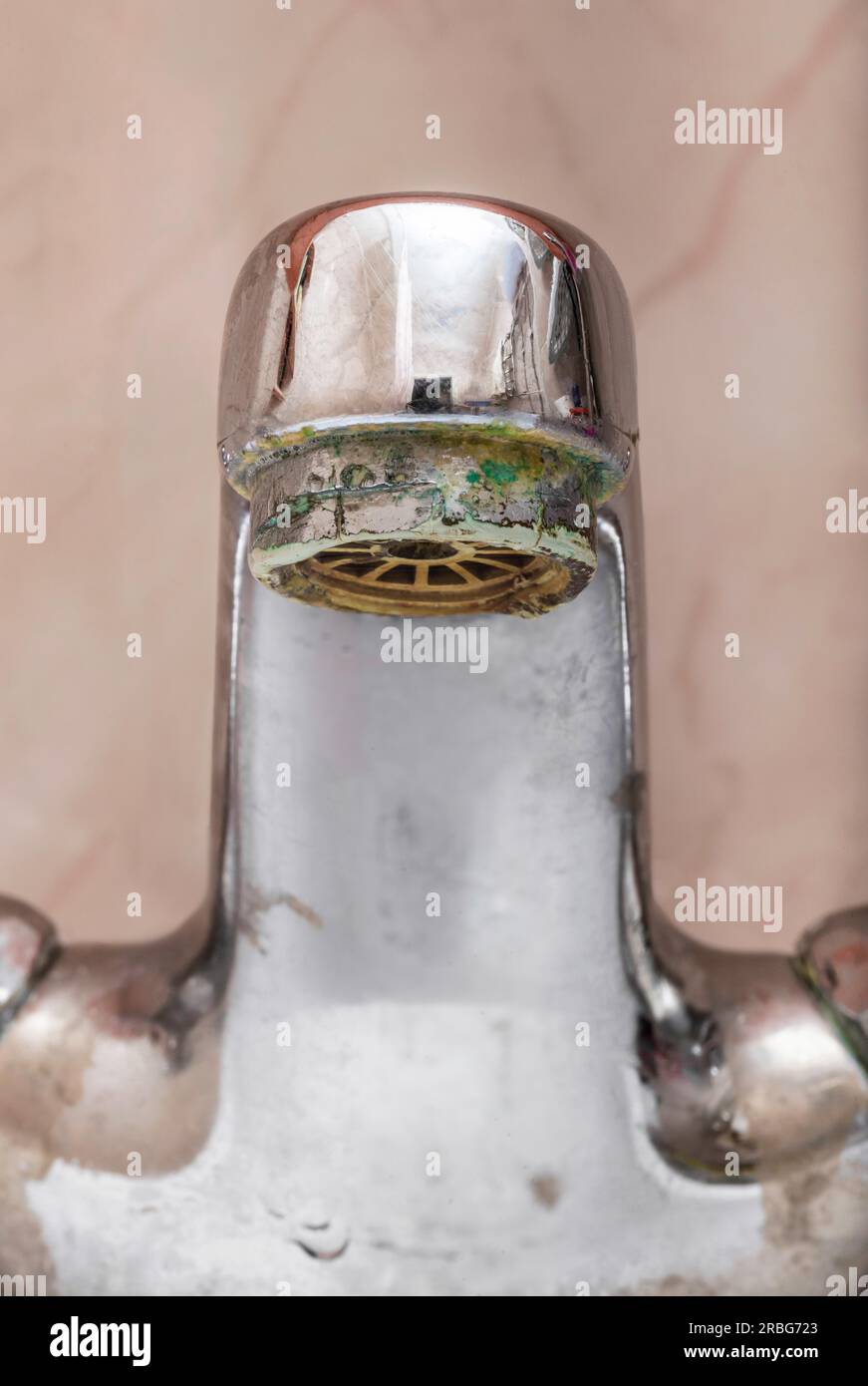 Vertikales Makrobild eines geschlossenen Wasserhahns über einem weißen Waschbecken im Badezimmer Stockfoto