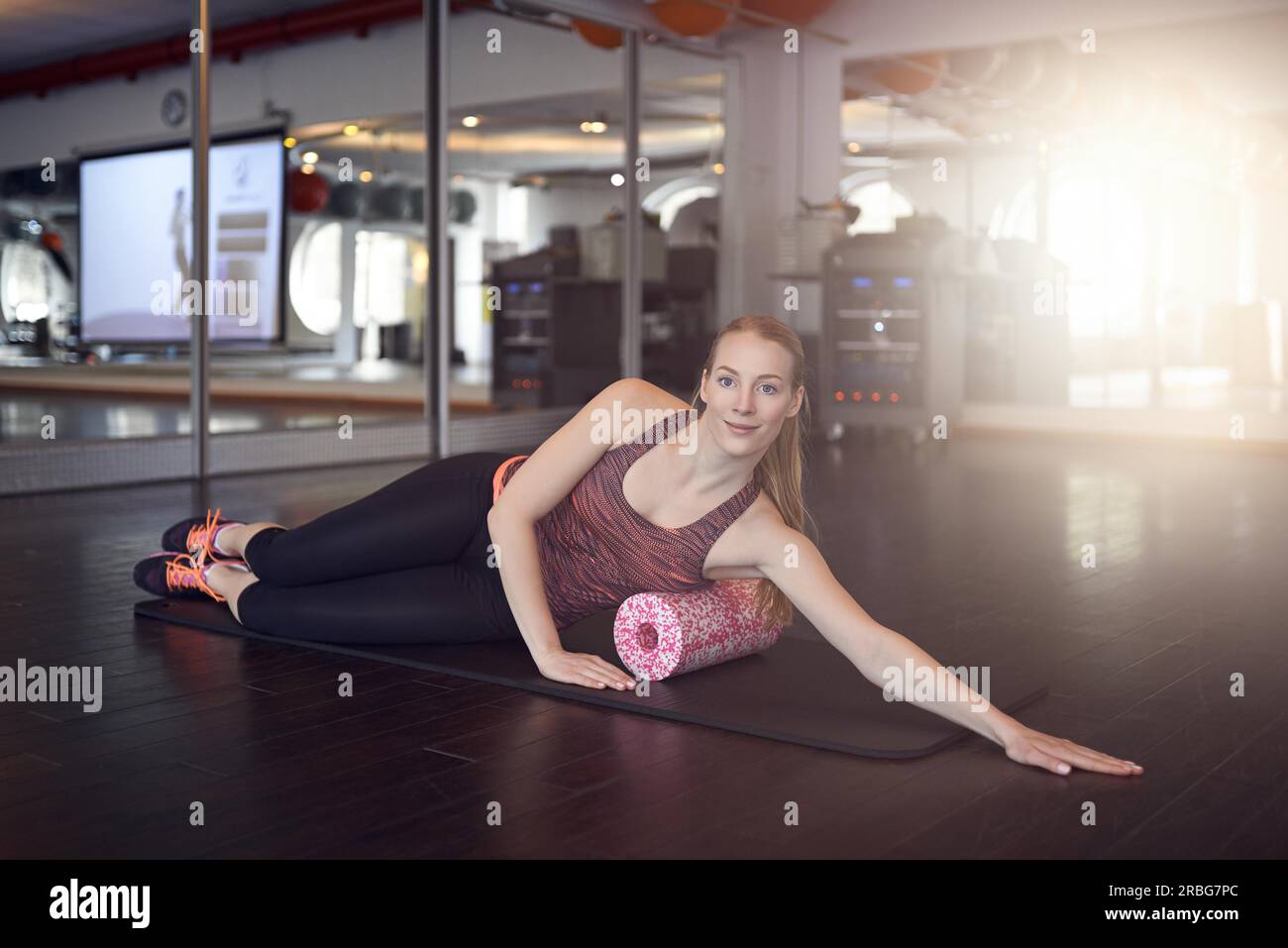 Frau im ärmellosen Hemd und schwarze Leggings im Fitness-Studio Sport mit Schaum oder Faszie Roll und Blick in die Kamera Stockfoto