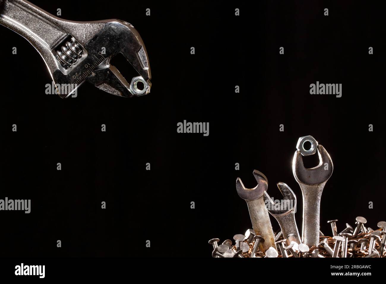 Konzeption eines verstellbaren Schraubenschlüssels, der Babyschlüssel in einem Nagelnest füttert Stockfoto