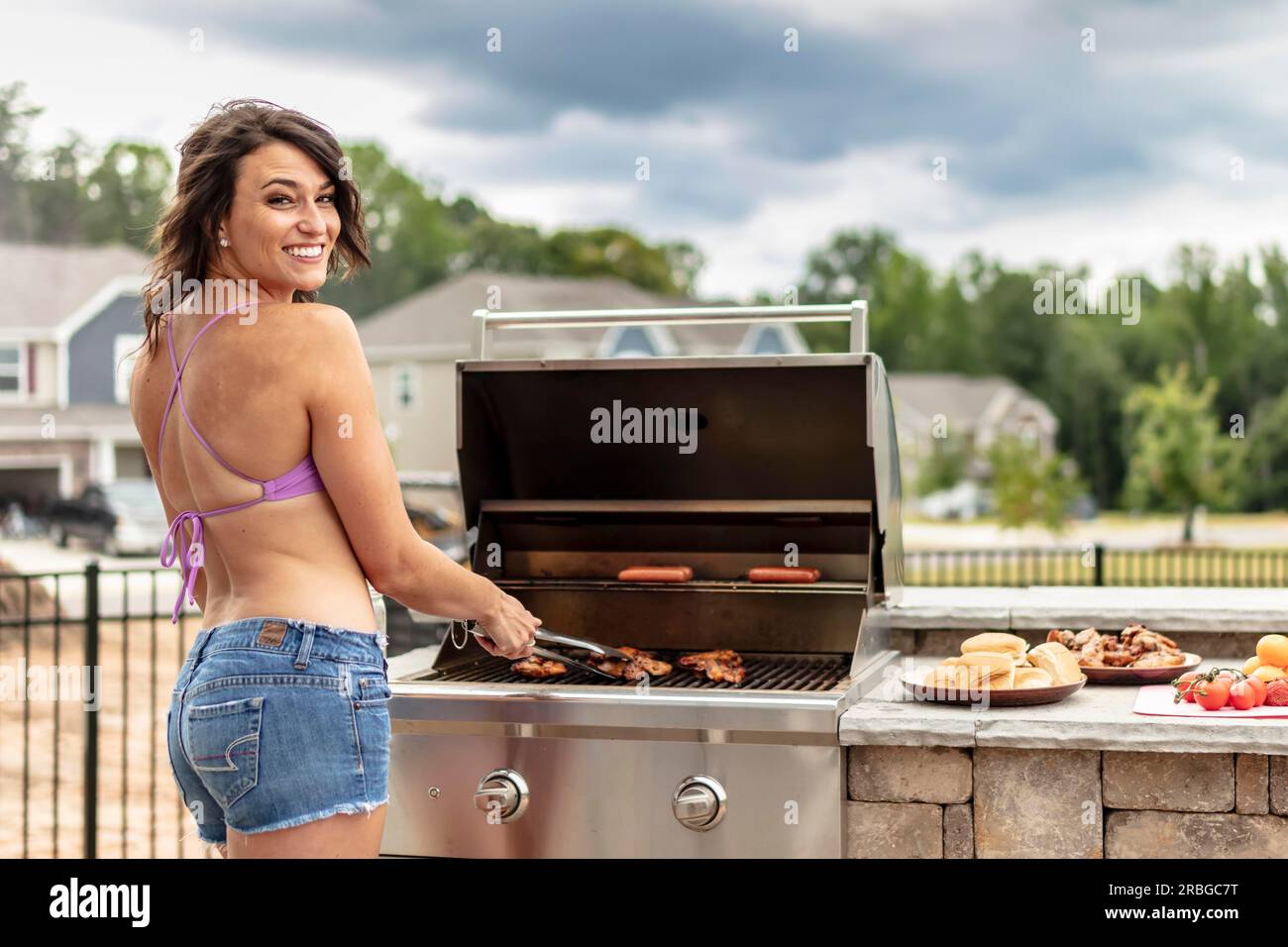 Ein wunderschönes brünettes Model, das einen Tag draußen genießt, während es auf einem Grill kocht Stockfoto