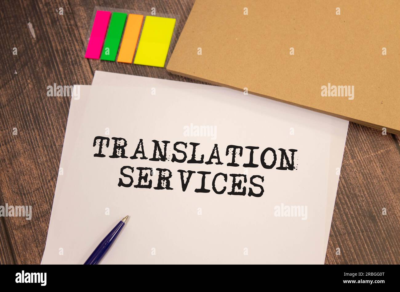 Auf hellem Hintergrund, goldgerahmte Gläser, eine Blume im Topf, ein grünes Notizbuch, ein roter Stift und ein braunes Notizbuch mit den TEXTÜBERSETZUNGSDIENSTEN. Bu Stockfoto