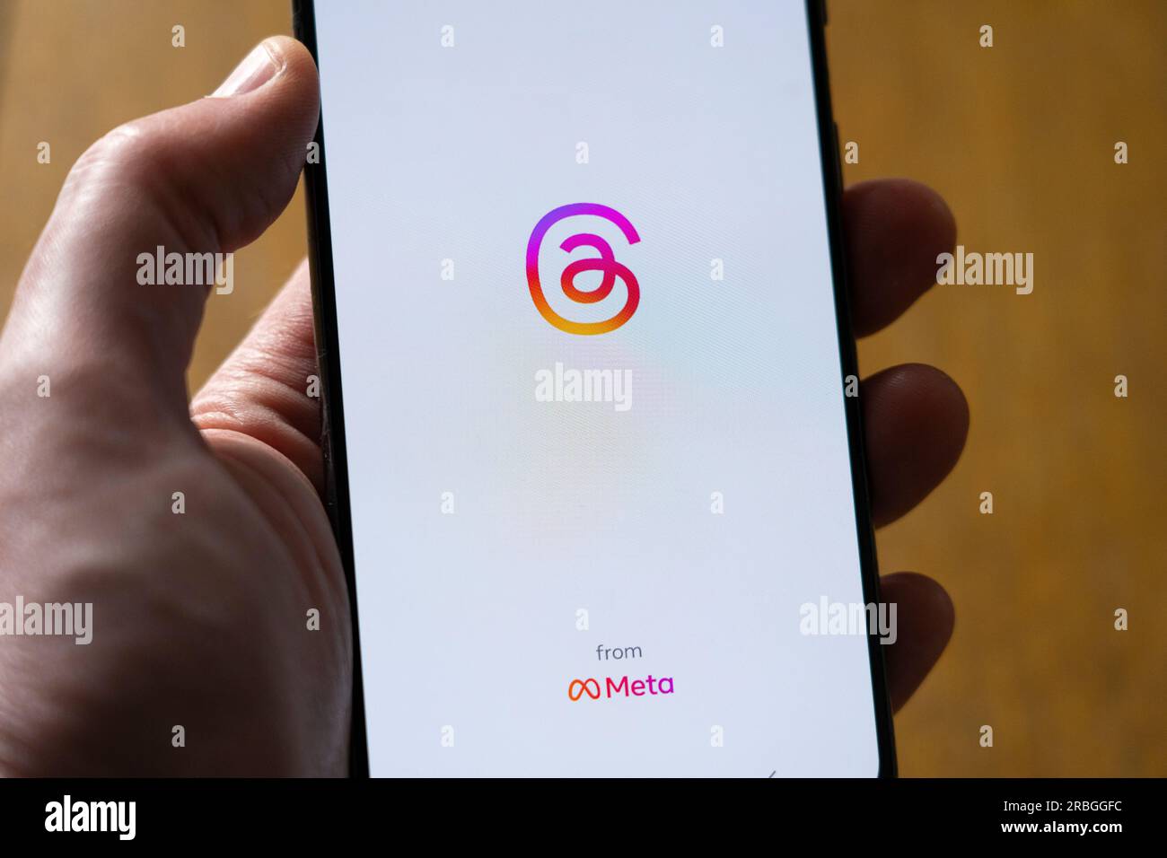 Die Hand eines Mannes, der ein Smartphone hält und die Instagram Threads App von Meta auf weißem Hintergrund mit Kopierbereich zeigt. UK Stockfoto