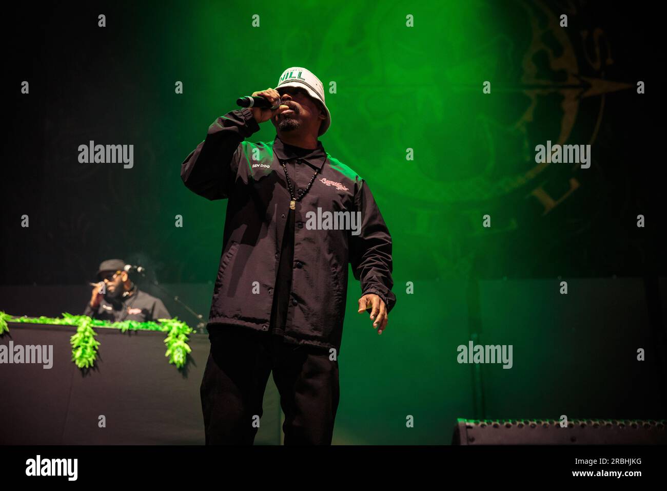 Sen Dog von Cypress Hill tritt auf der Bühne auf, mit einem Eimerhut, einem schwarzen Trainingsanzug und einem Mikrofon. Stockfoto