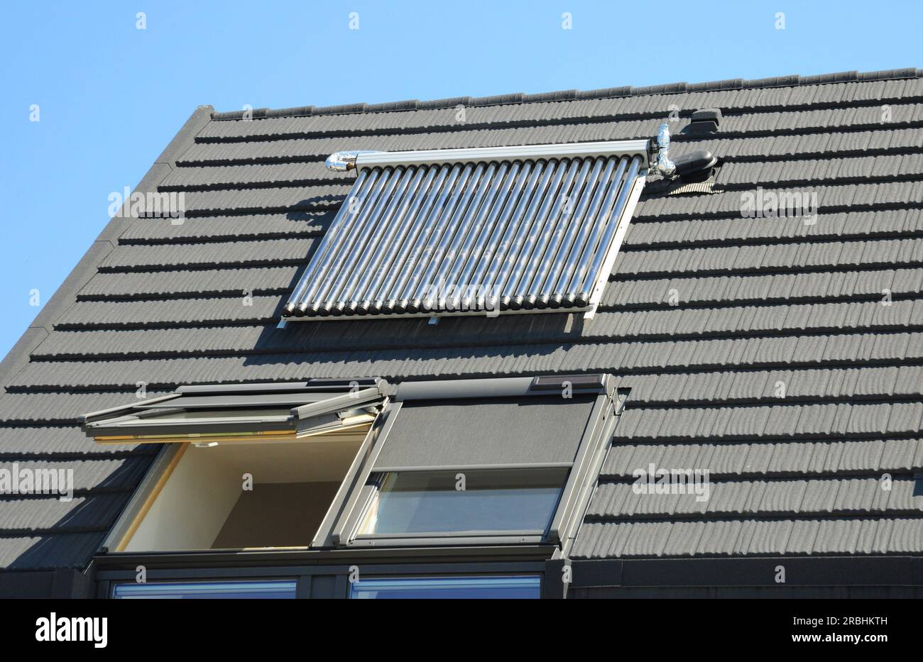 Bei der Nahaufnahme der Solarwasserheizung (SWH) auf dem Dach des Hauses wird Wasser durch Sonnenlicht mithilfe eines solarthermischen Kollektors erwärmt. Dachfenster mit Alumin Stockfoto