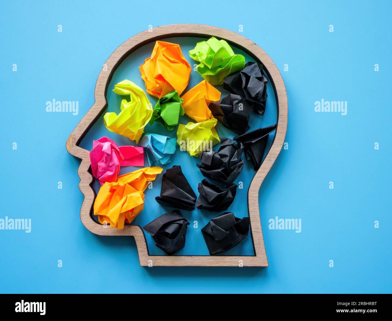 Konzept negativer und positiver Gedanken. Kopfform mit farbigen und schwarzen Papierkugeln. Stockfoto