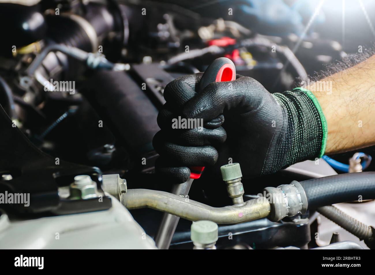 Automechaniker in schwarzen Handschuhen, die einen Automotor reparieren. Automechaniker, der an einem Motor arbeitet. Stockfoto