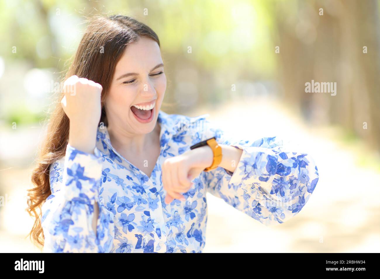 Aufgeregte Frau, die gute Nachrichten feiert und Smartwatch überprüft Stockfoto