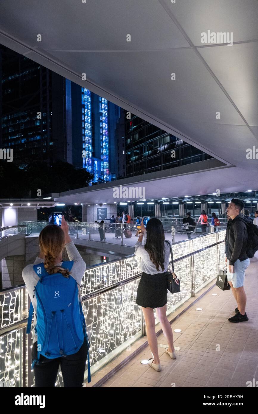 Touristen fotografieren die Skyline im Hafen-Einkaufszentrum IFC Mall at Night, Hongkong, China, Asien. Foto: Rob Watkins Stockfoto