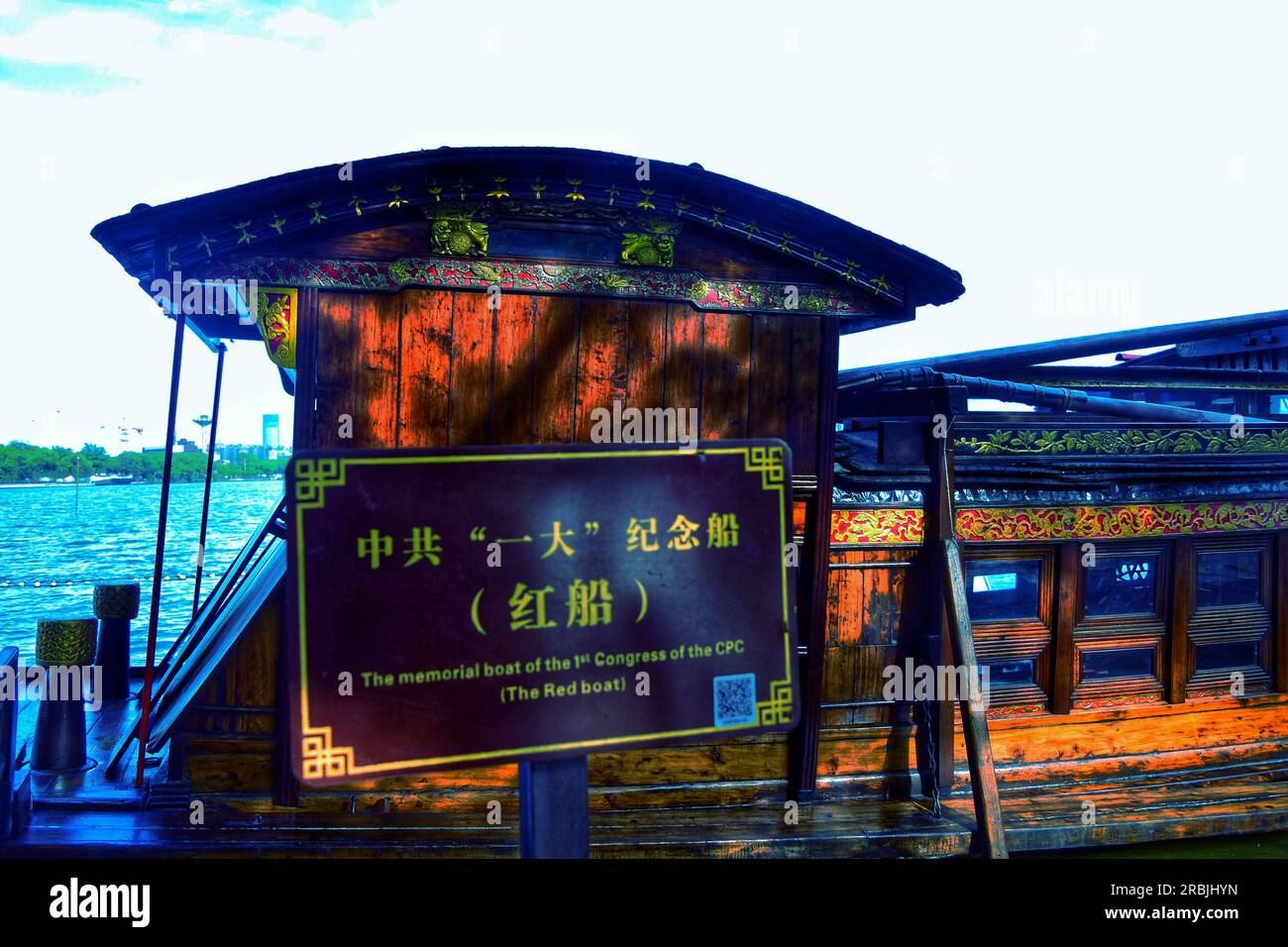 Erleben Sie die ruhige Schönheit, während ein traditionelles Boot anmutig entlang des Flusses segelt und sich in der warmen Umarmung des Sonnenlichts im Freien in China sonnt. Stockfoto