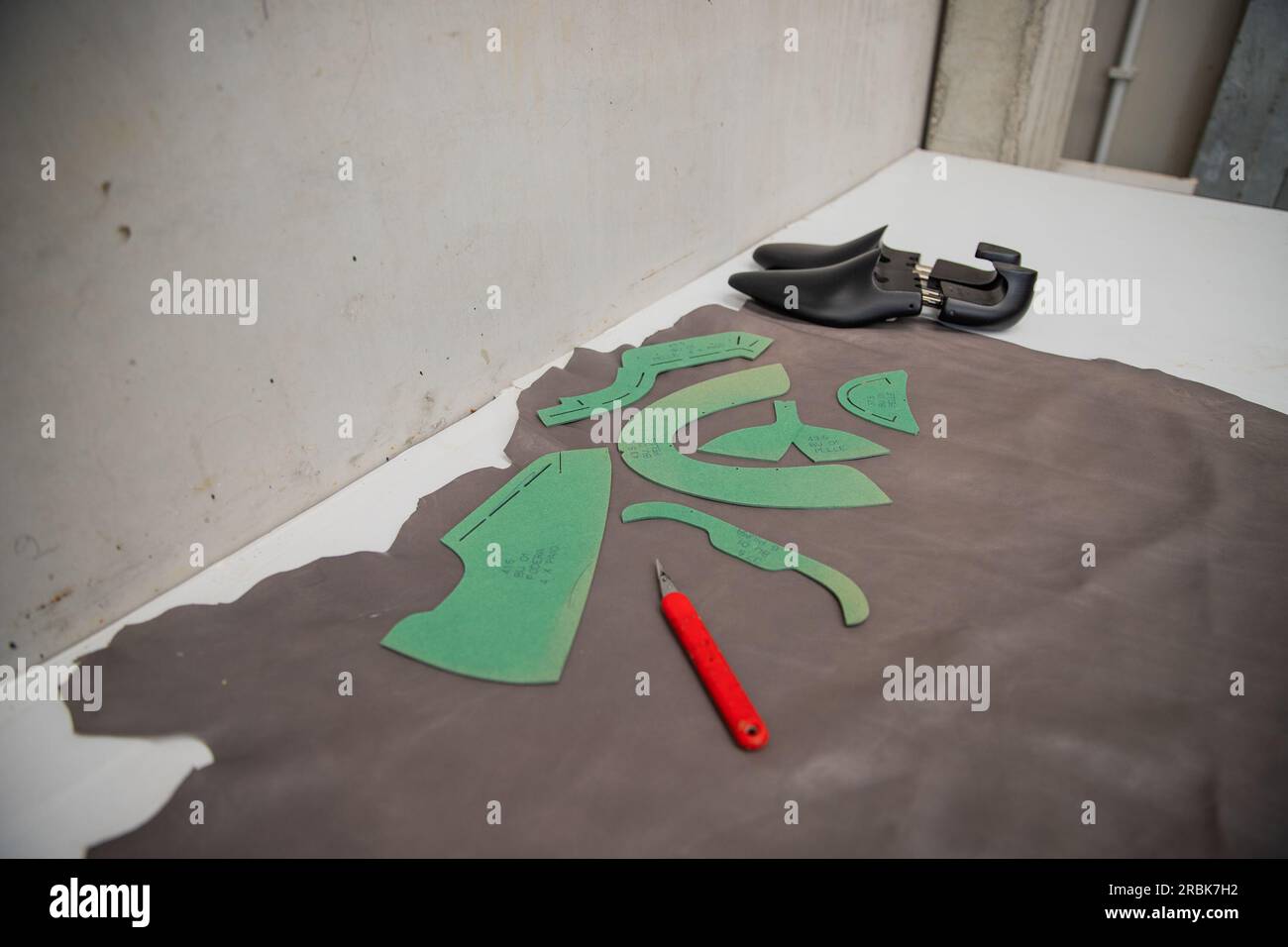 Arbeitstisch zur Herstellung von Schuhen mit Leder und Leisten sowie eine Schneidemaschine, Modebranche Stockfoto