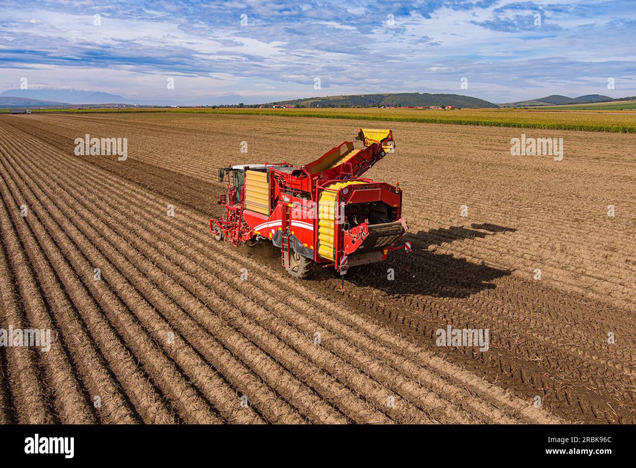 Große Kartoffelerntemaschine, die von einem Traktor gezogen wird, der eine Feile bearbeitet Stockfoto