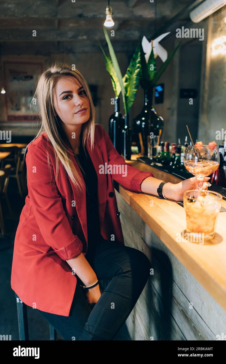 Blonde Girl schaut in einer Cocktailbar auf die Kamera. Stockfoto