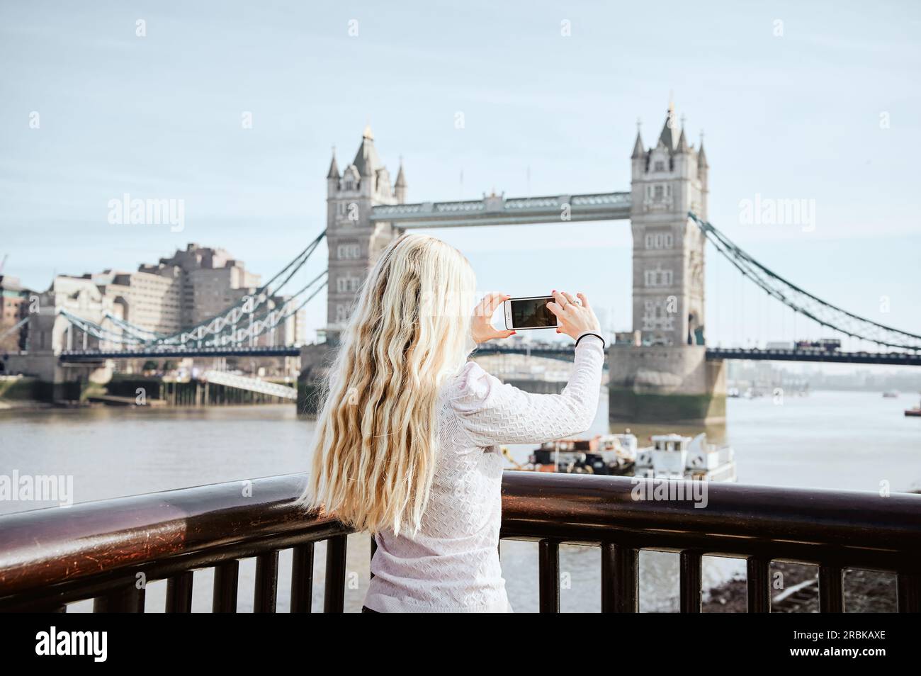 Langhaarige blonde Frau, die ein Foto von der Tower Bridge macht Stockfoto