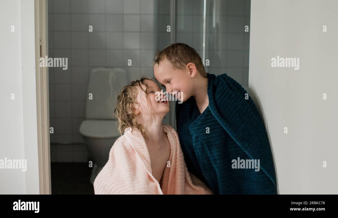 Mädchen und Junge standen vor dem Badezimmer in Handtüchern und lachten und spielten Stockfoto