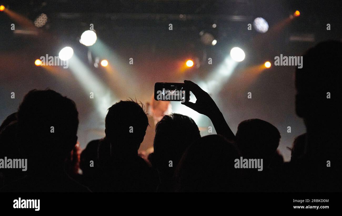 Silhouette einer Gruppe von Leuten an einem Konzertsaal, die die Bühne beobachten Stockfoto