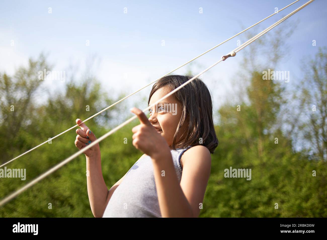 Junge Asiatin, die in der Sommersonne mit Zeltlinien spielt Stockfoto