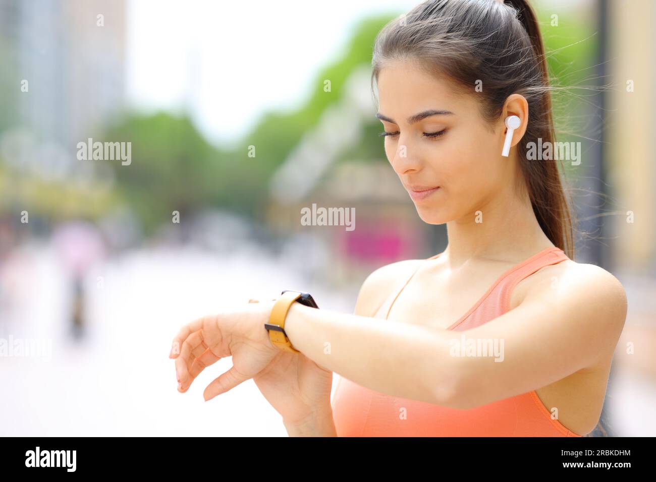 Läufer mit Ohrstöpseln, der die Smartwatch auf der Straße überprüft Stockfoto