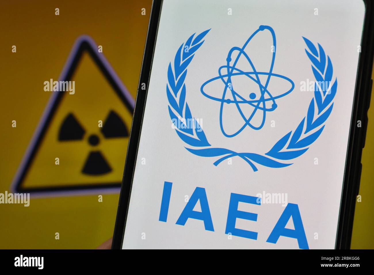 Ukraine. 07. Juli 2023. In dieser Fotoabbildung ist das Logo der Internationalen Atomenergie-Organisation (IAEA) auf einem Smartphone zu sehen, und im Hintergrund ist das Zeichen radioaktiv. Kredit: SOPA Images Limited/Alamy Live News Stockfoto