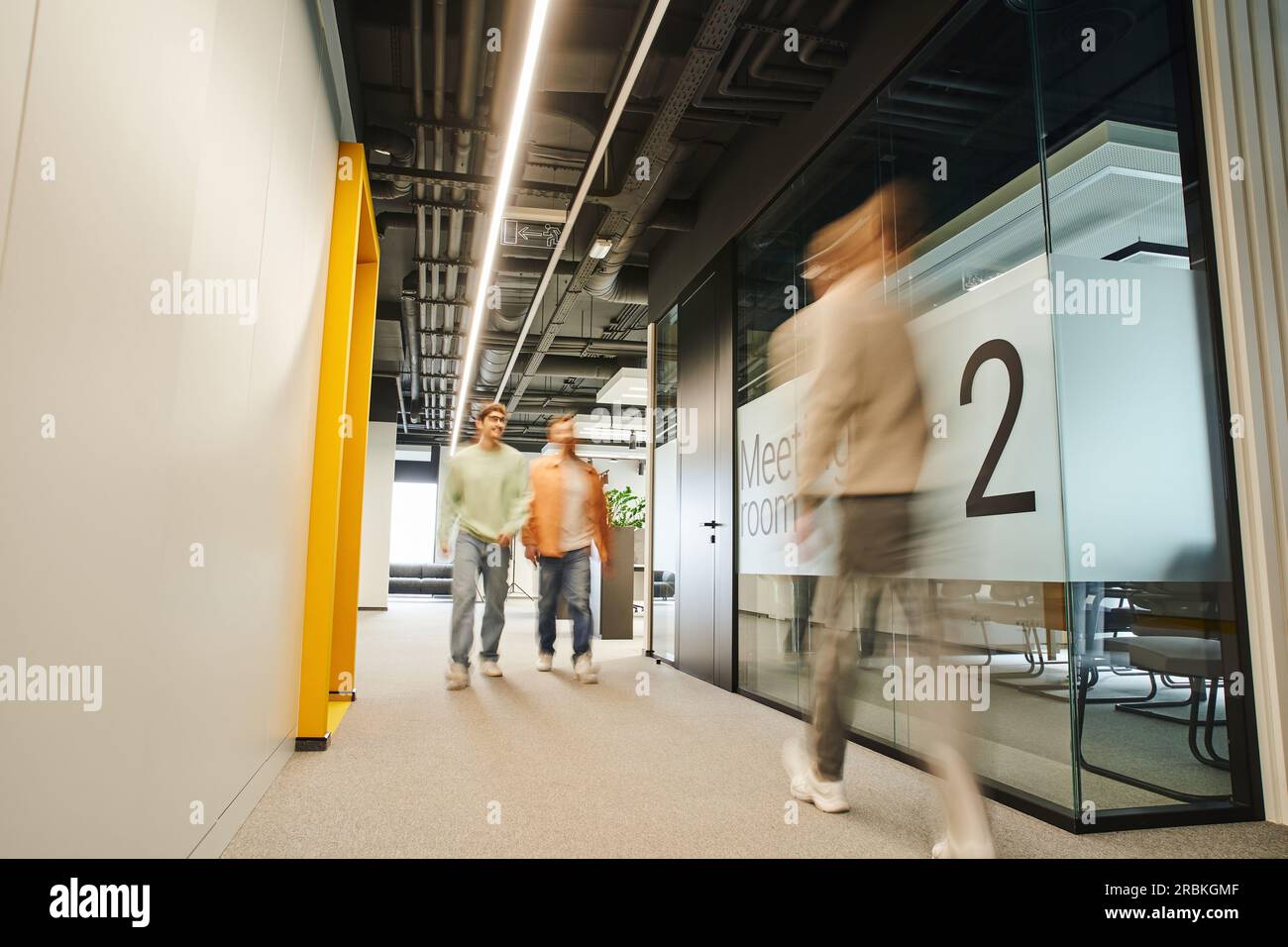 Bewegungsunschärfe von modernen Geschäftsleuten, die auf dem Flur entlang des Tagungsraums in einer modernen, kooperativen Umgebung mit High-Tech-Interieur und dynamischem Bus arbeiten Stockfoto