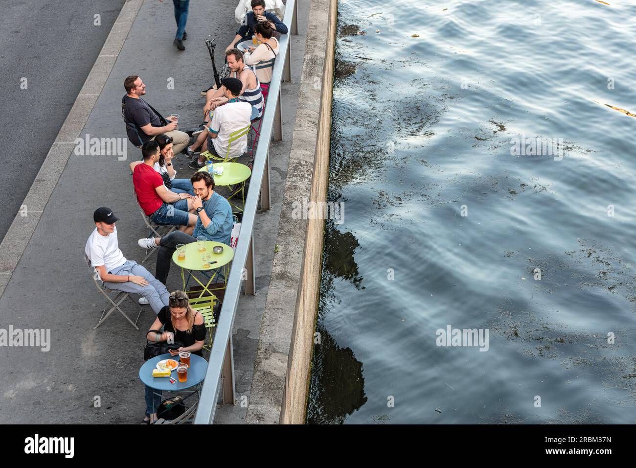 Die Menschen essen, trinken und unterhalten sich am Flussufer der seine am rechten Ufer der Voie Georges Pompidou gegenüber der Ile Saint-Louis. Paris. Stockfoto
