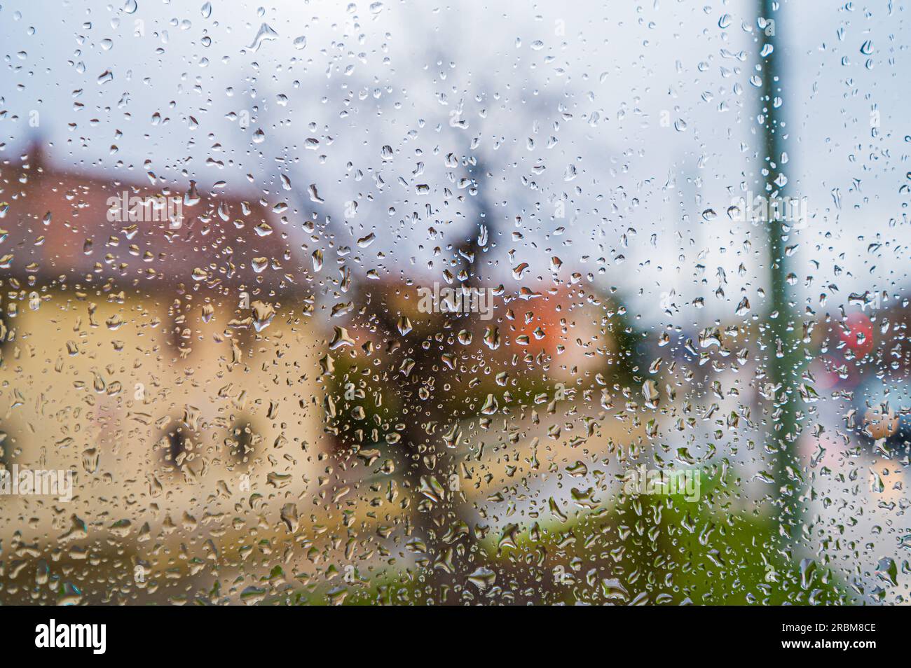 Wassertropfen auf einer Fensterscheibe eines Apartmentgebäudes mit Blick auf ein Bauernhaus und eine Kreuzung, Jena, Thüringen, Deutschland Stockfoto