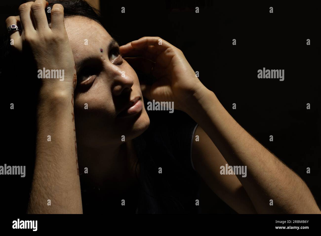 Wunderschönes indisches Modell mit dramatischem dunklen Licht und Schatten, die in den Himmel blicken. Stockfoto