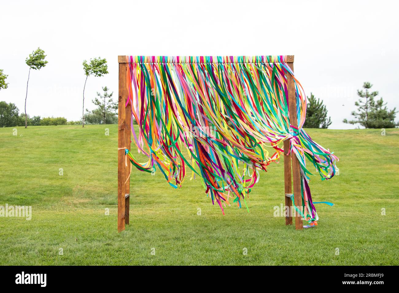 Bunte Bänder, die an einem Holztor mit den Parks auf dem Gras verbunden sind, fliegen im Sommer in der Ukraine im Park in der Luft, Dekor für eine Party im Pa Stockfoto