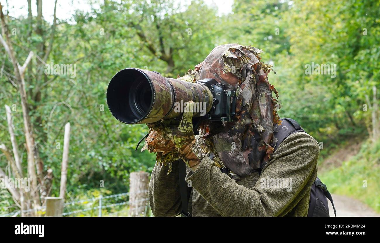 Wildtierfotograf in Tarnkleidung Kopfbedeckung und Handschuhen. Stockfoto