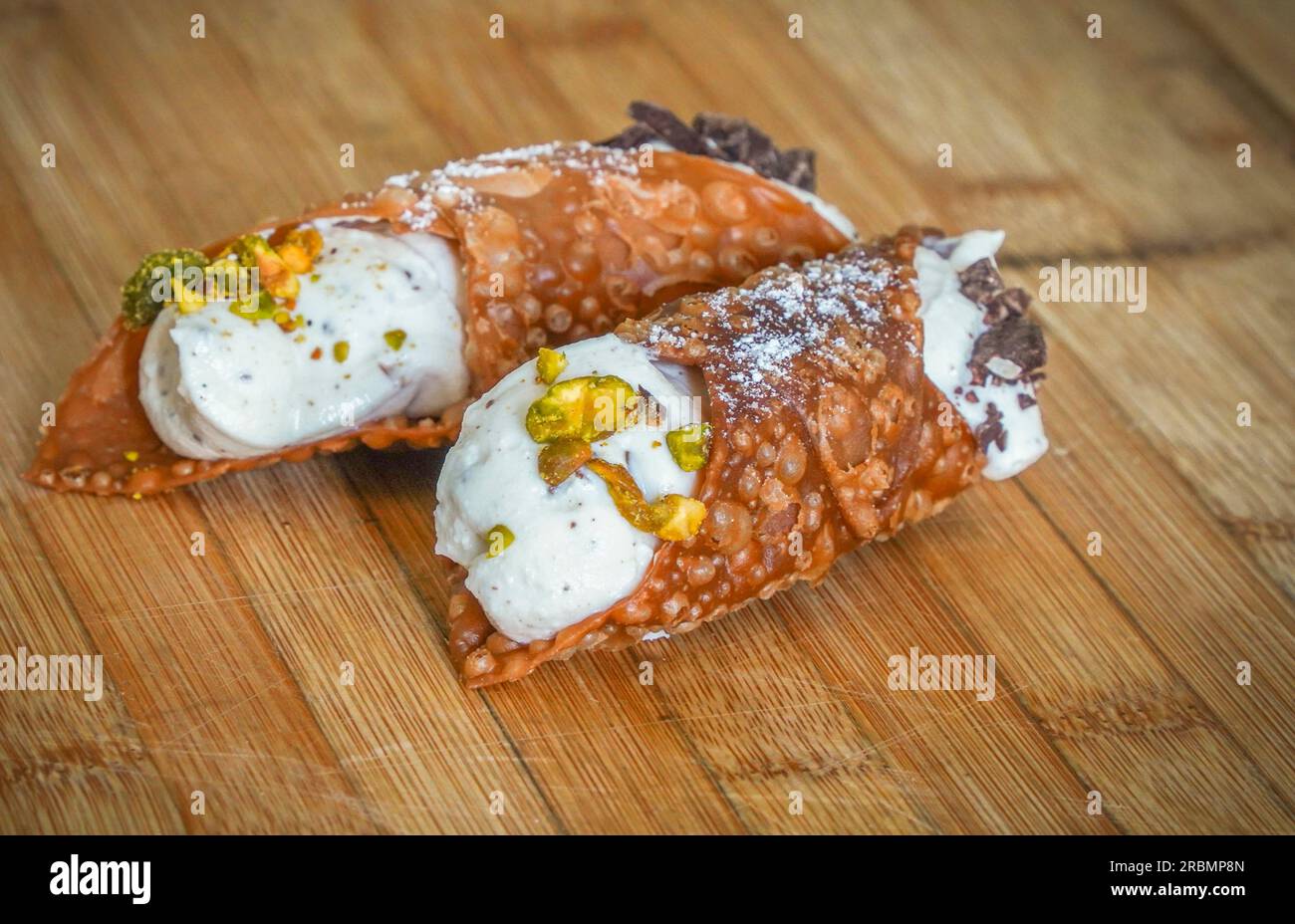 Ein italienischer Cannoli gefüllt mit Ricotta Creme auf Holzbrett. Stockfoto