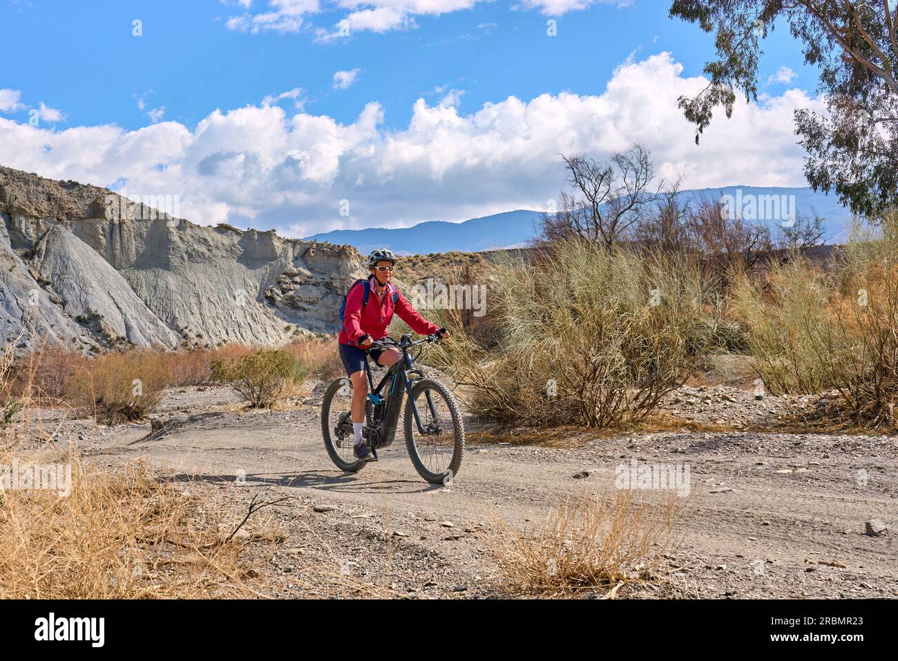 Nette, aktive Seniorin mit ihrem elektrischen Mountainbike auf einer Wandertour durch die Wüste von Tabernas bei Almeria, Andlusia, Spanien Stockfoto