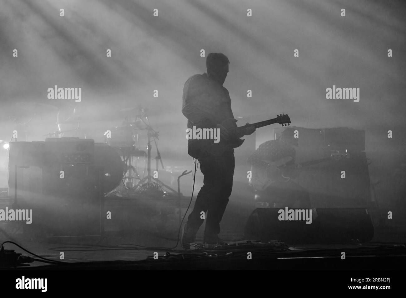 Eine Silhouette des Rockmusikers Gitarrist während eines Live-Konzerts im dunklen Licht. Dunkler Hintergrund, Rauch, Scheinwerfer Stockfoto