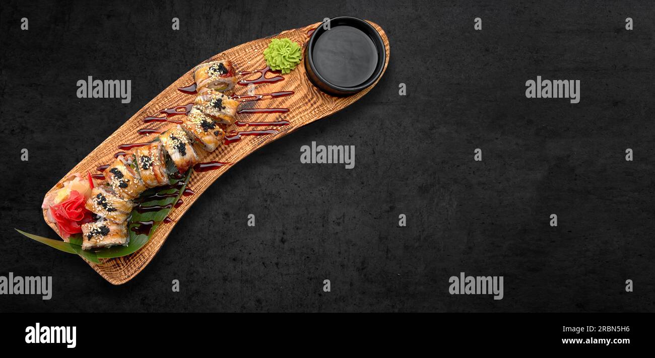 Klassisches Sushi-Brötchen mit Meeresfrüchten, Sojasauce, Wasabi und Ingwer. Dunkler Hintergrund, horizontales Banner Stockfoto