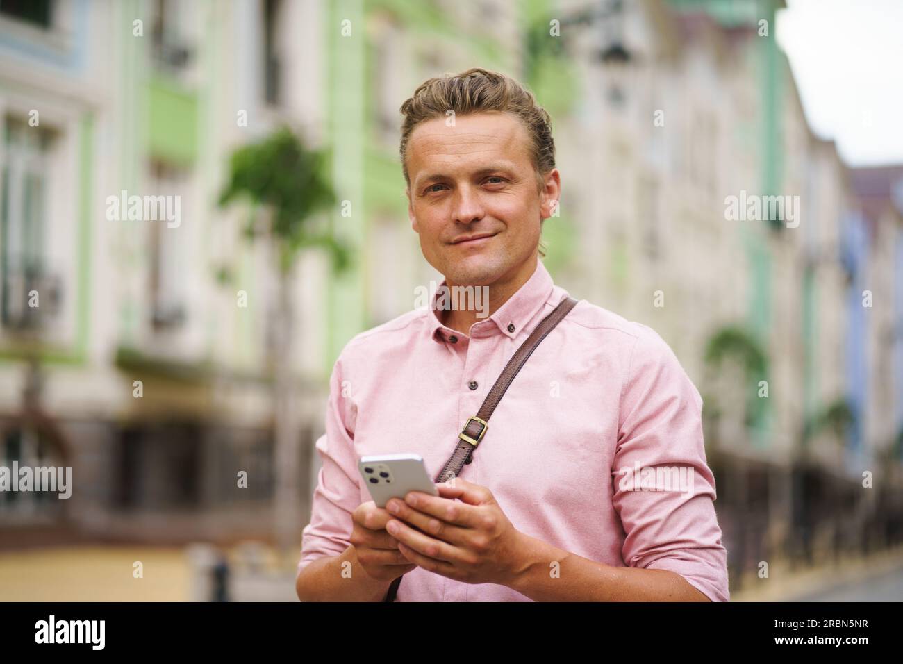 Ein Mann mittleren Alters, der im Freien eine Nachricht schrieb. Mit seinem Mobiltelefon in der Hand nutzt er digitale Kommunikation, um sich mit anderen in der städtischen Umgebung zu vernetzen. Hochwertiges Foto Stockfoto