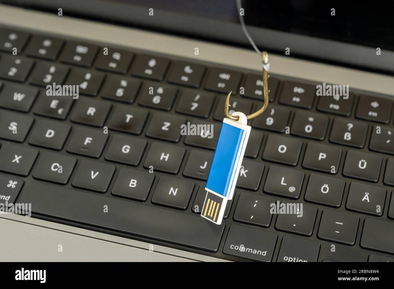 Visualisierung von Cyberkriminalität, Spionage und Datenverlust durch einen USB-Stick auf einem Angelhaken mit Computertastatur im Hintergrund Stockfoto