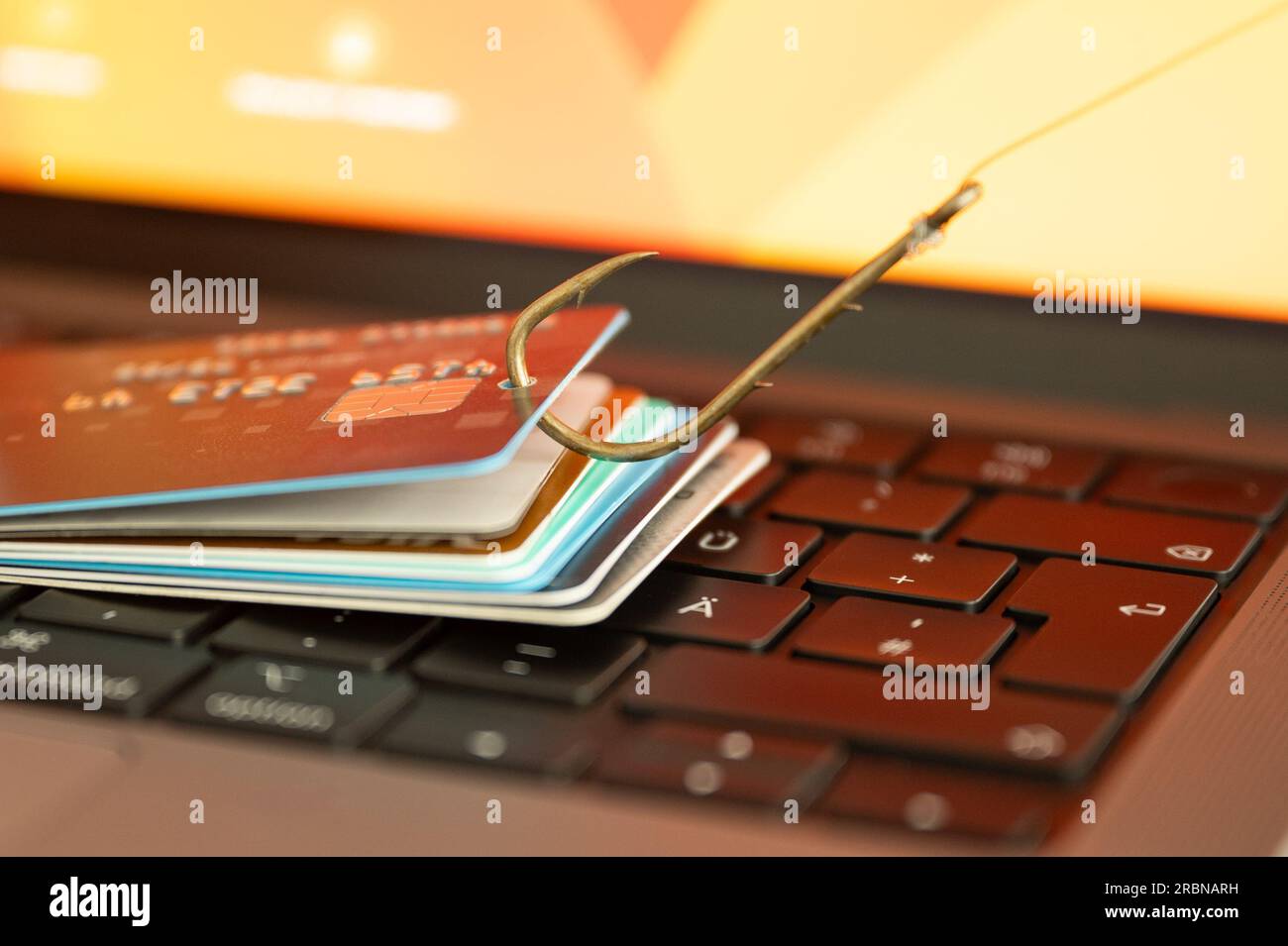 Visualisierung von Phishing und Online-Betrug durch eine Phishing-Kreditkarte auf einer PC-Tastatur, die an einem Fischerhaken hängt Stockfoto