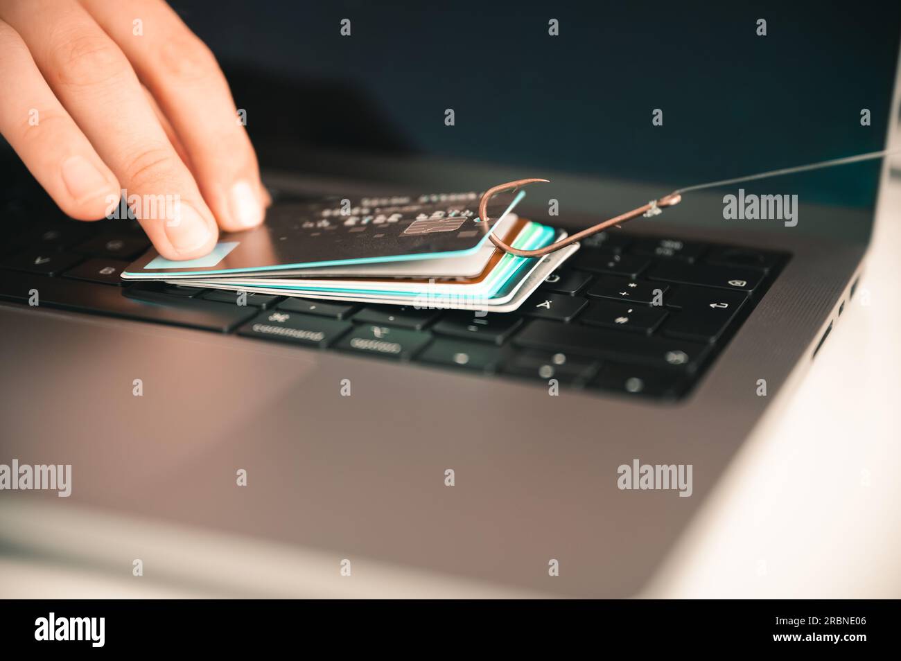 Visualisierung einer Person, die versucht, Phishing und Online-Betrug zu verhindern, indem sie eine undichte Kreditkarte auf einer PC-Tastatur hält, die an einem Fischerhaken hängt Stockfoto