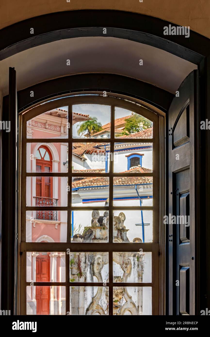 Historische Gebäude in der Stadt Ouro Preto in Minas Gerais durch ein altes Fenster im Kolonialstil Stockfoto