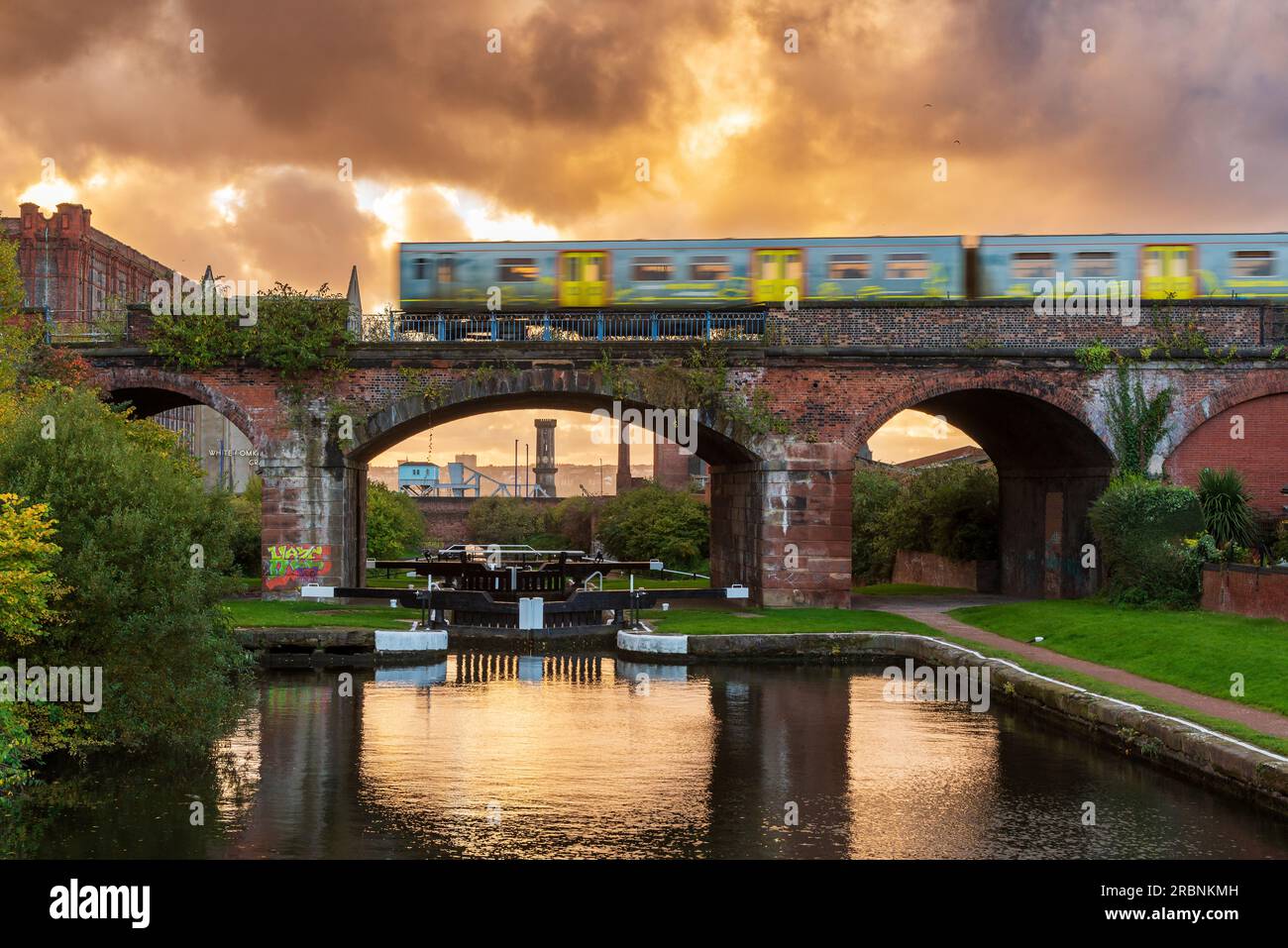 Die letzte Schleuse des Leeds Liverpool-Kanals, wenn er die Docks von Liverpool erreicht, mit dem Merseyrail-Zug, der über das Viadukt fährt. Stockfoto