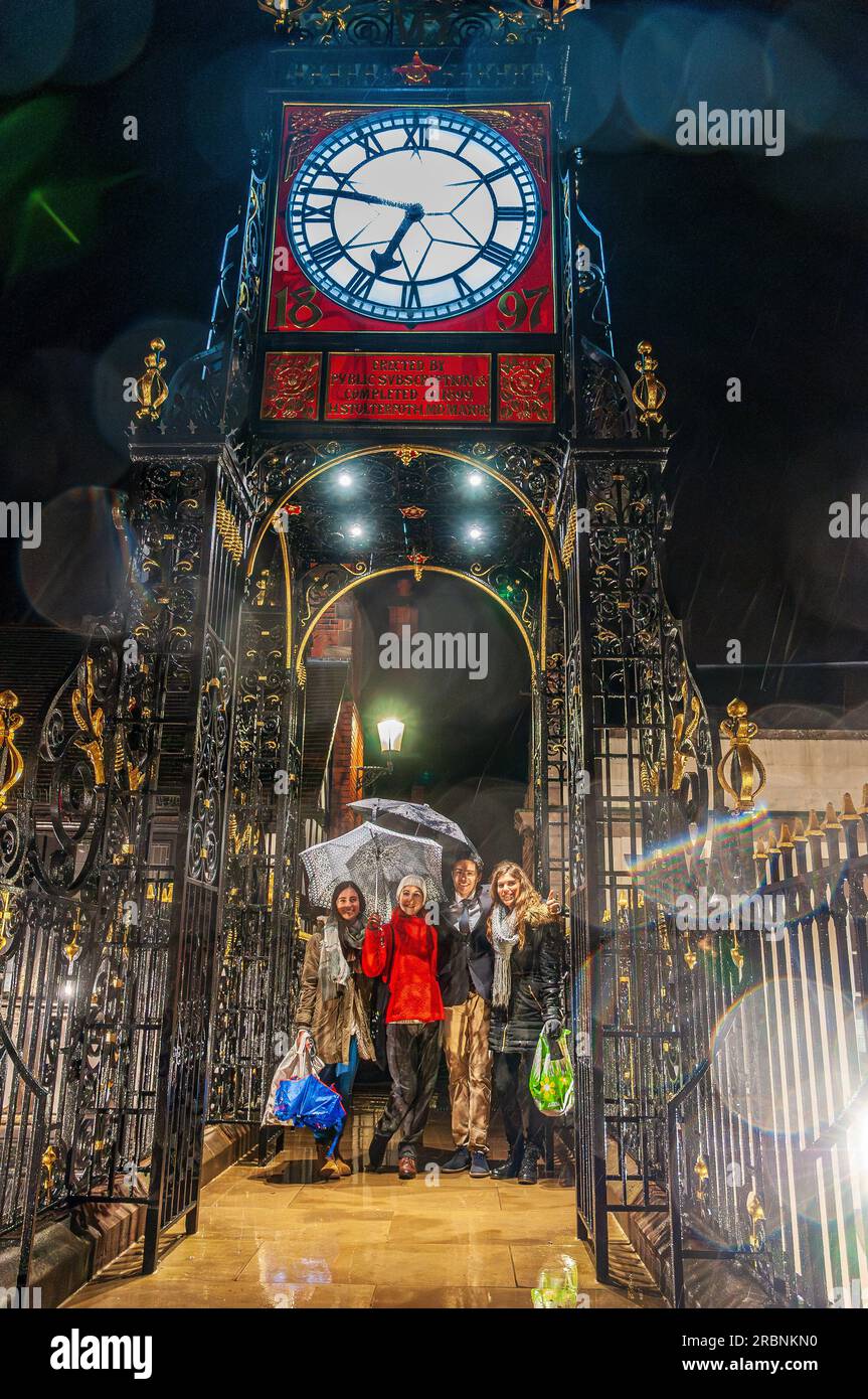 Reveller unter der Eastgate-Uhr in Chester an einem regnerischen Abend. Stockfoto