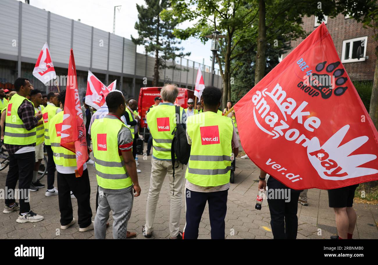 Hamburg, Deutschland. 10. Juli 2023. Mitarbeiter von Amazon stehen während einer Vorführung unter dem Titel „Make Amazon Pay! Für gute und gesunde Arbeit bei Amazon!“ Vor der S-Bahn-Station Veddel, um zum Amazon-Vertriebszentrum in Hamburg-Veddel zu laufen. Die Gewerkschaft Verdi fordert gemeinsam mit anderen politischen Initiativen die Mitarbeiter von Amazon auf, zu demonstrieren und ihre Arbeit einzustellen. Kredit: Christian Charisius/dpa/Alamy Live News Stockfoto
