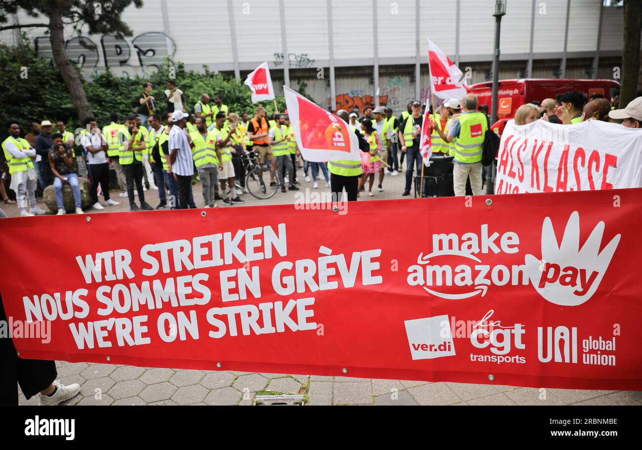Hamburg, Deutschland. 10. Juli 2023. Mitarbeiter von Amazon stehen während einer Vorführung unter dem Titel „Make Amazon Pay! Für gute und gesunde Arbeit bei Amazon!“ Vor der S-Bahn-Station Veddel, um zum Amazon-Vertriebszentrum in Hamburg-Veddel zu laufen. Die Gewerkschaft Verdi fordert gemeinsam mit anderen politischen Initiativen die Mitarbeiter von Amazon auf, zu demonstrieren und ihre Arbeit einzustellen. Kredit: Christian Charisius/dpa/Alamy Live News Stockfoto