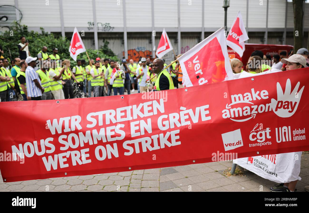 Hamburg, Deutschland. 10. Juli 2023. Mitarbeiter von Amazon stehen während einer Vorführung unter dem Titel „Make Amazon Pay! Für gute und gesunde Arbeit bei Amazon!“ Vor der S-Bahn-Station Veddel, um zum Amazon-Vertriebszentrum in Hamburg-Veddel zu laufen. Die Gewerkschaft Verdi fordert gemeinsam mit anderen politischen Initiativen die Mitarbeiter von Amazon auf, zu demonstrieren und ihre Arbeit einzustellen. Kredit: Christian Charisius/dpa/Alamy Live News Stockfoto