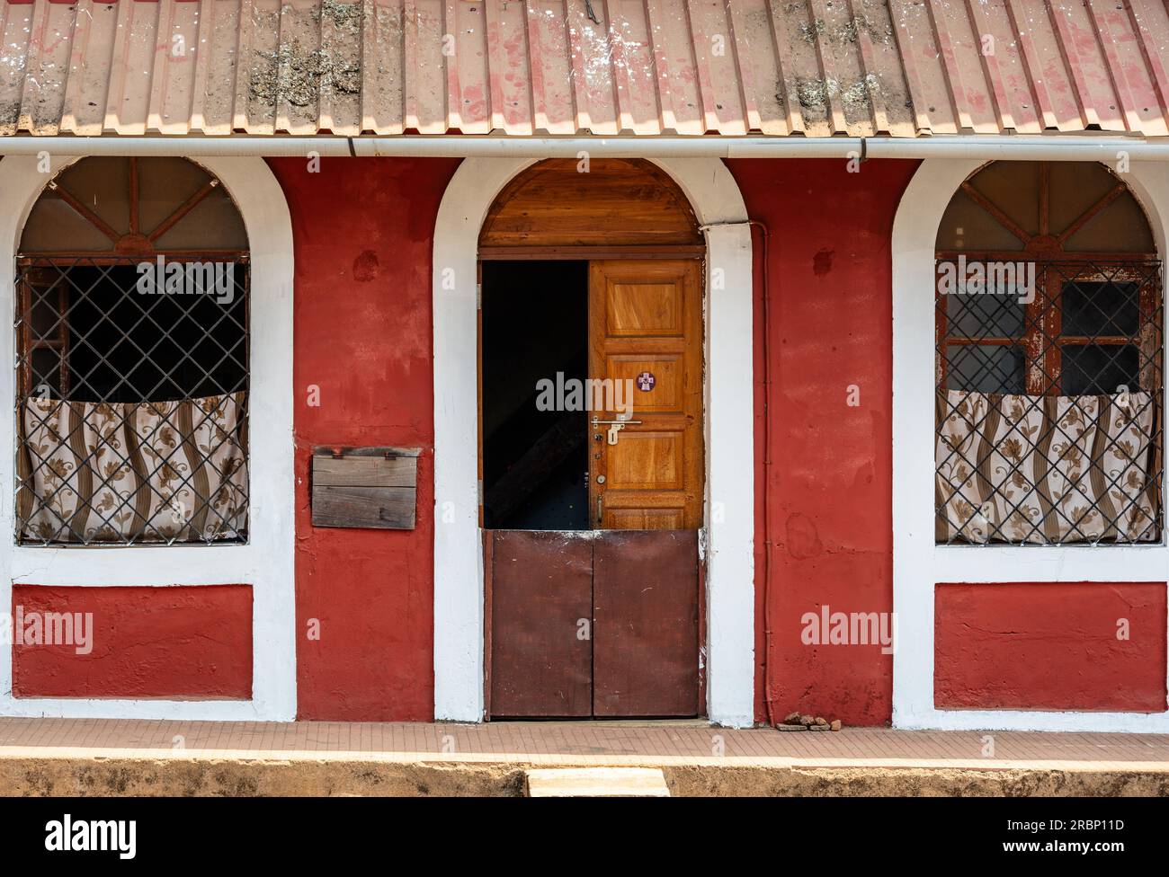 Ein Teleobjektiv mit der Vorderseite eines roten Hauses mit weißen Bogentüren und Fensterrahmen. Stockfoto
